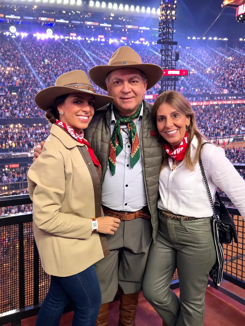 Lara ao lado dos pais em um rodeio, todos de chapéu e lenço no pescoço