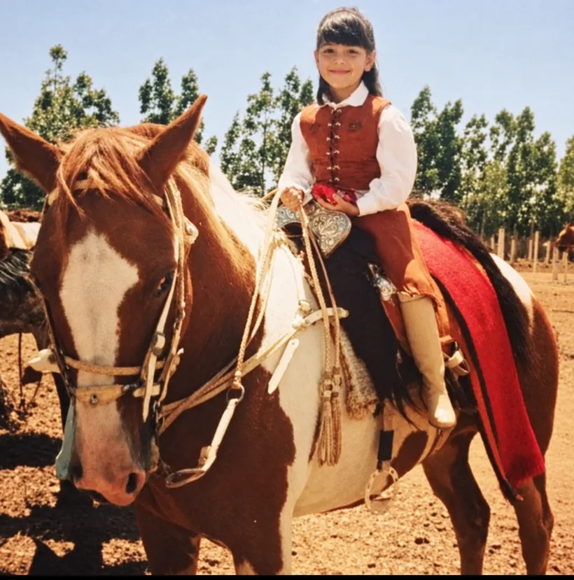 Lara ainda criança, com traje tradicional gaúcho, montada em um cavalo